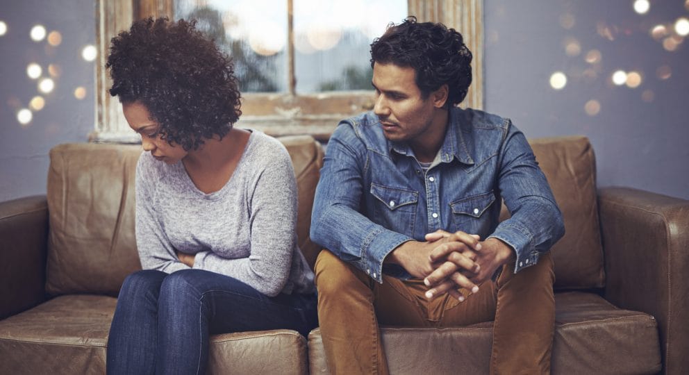 A photo of a couple on a couch in their home, presumably disagreeing from a fight.