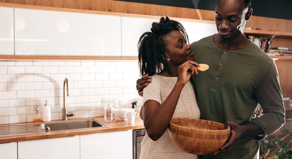 Improve your relationship with Gottman Bids. Image of couple laughing together in the kitchen.