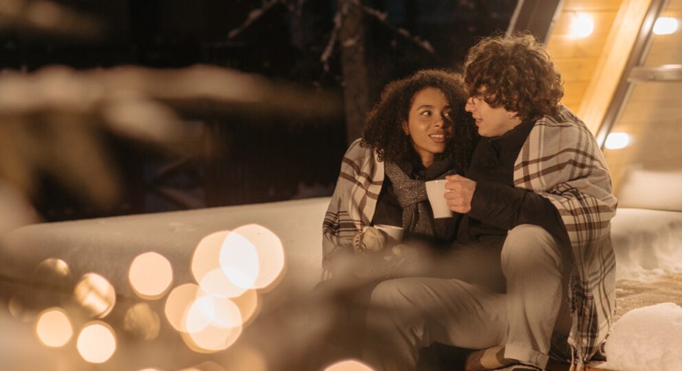 Why can't we compromise? Image of couple cuddling under a blanket under lights outside.