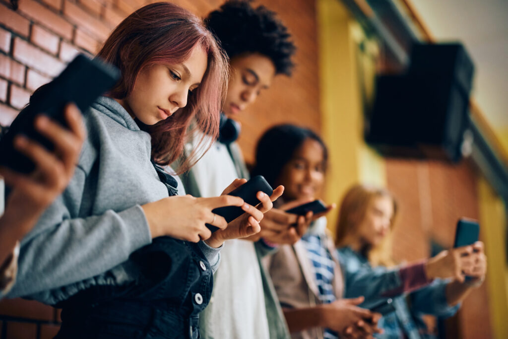 Group of teens all on their phones and not interacting with each other