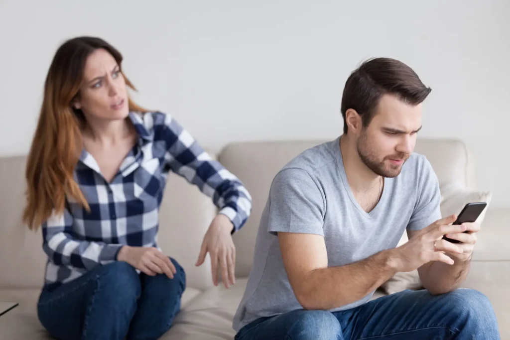Woman trying to get her partner to listen to her, but he is focused on his phone.