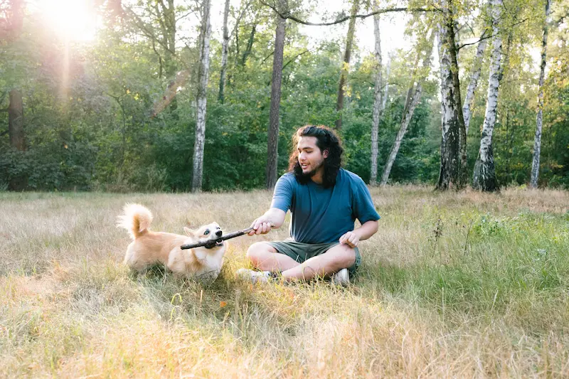 Man who is happily laying with his dog outside is preparing himself for a healthy relationship by learning to enjoy alone time.