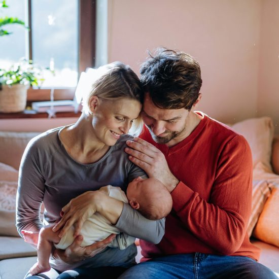 Close-up of parents cuddling their newborn baby.