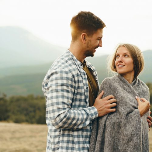 Happy loving couple hiking and hugging in mountains